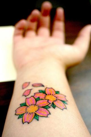 Цветная тату на запястье девушки в виде цветков сакуры