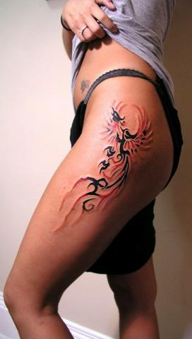 Татуировка на бедре девушки в виде птицы феникс