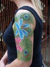 Цветная тату на плече девушки - перья и лилии