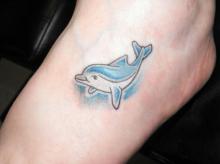 Тату в виде голубого дельфина на ноге девушки